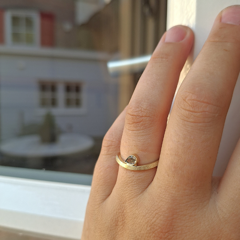 Gouden golvend minimalistische ring met een druppelvormige bruine diamant , als trouwring, aanschuifring of verlovingsring. tijdloos ontwerp door Goudsmederij Goedbloed foto op model