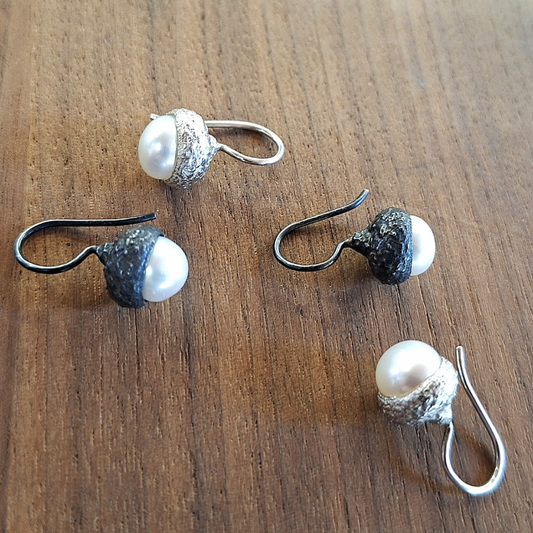 Zilveren oorbellen met eikenkap en daarin een witte zoetwaterparel als eikel gezet.  Natuurlijk organisch en klassiek design door Goudsmederij Goedbloed