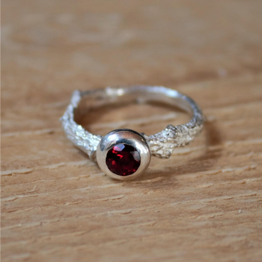 Zilveren eikentak als ring met een donutzetting en daarin een facetgeslepen rode granaat uit onze Forest Collectie. Handgemaakt door Goudsmederij Goedbloed
