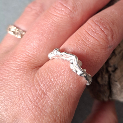 Een van zilver gevormd elvenbankje dat speels over de vinger golft als vloeibaar lava - op model-. Handgemaakt en duurzaam ontwerp door Goudsmederij Goedbloed