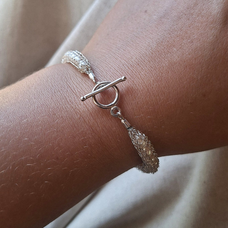 Handgeweven en gesmede zilveren armband met witte zoetwaterparels met sier kapittelsluiting foto op model Dragonstail design door Goudsmederij Goedbloed