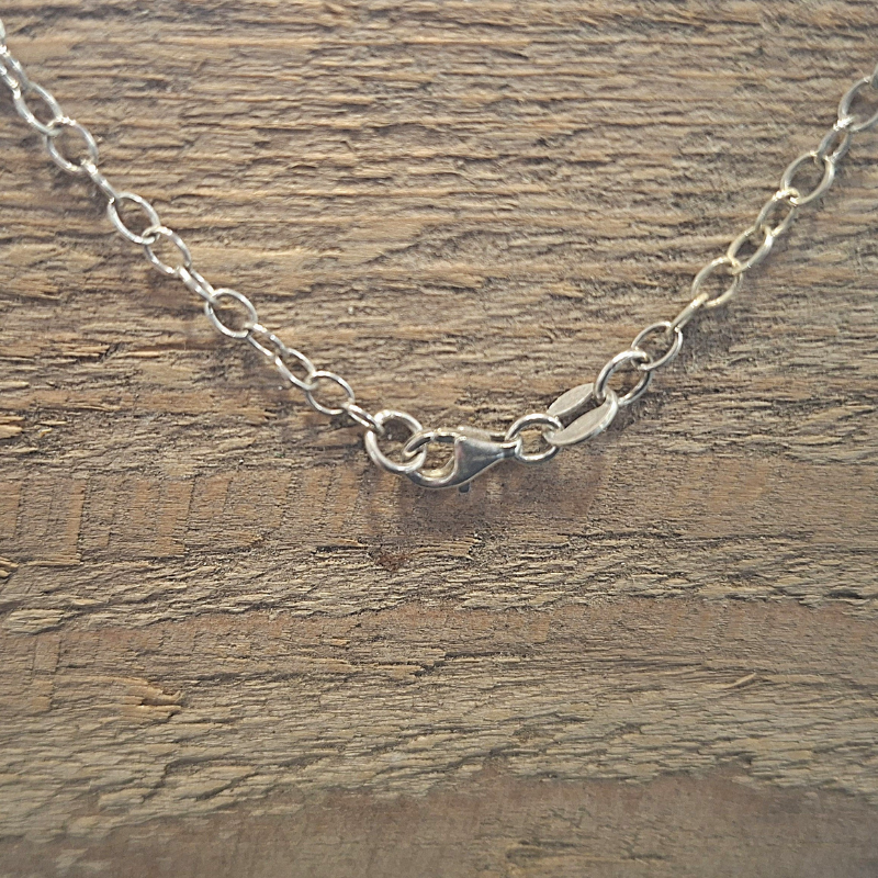 De karabijnsluiting voor het zilveren 925 ankerketting met een symmetrische tussenhanger met krulwerk en op het balanspunt een ophanging met een unieke druppelvormige rozenkwarts. Handgemaakt ontwerp door Goudsmederij Goedbloed